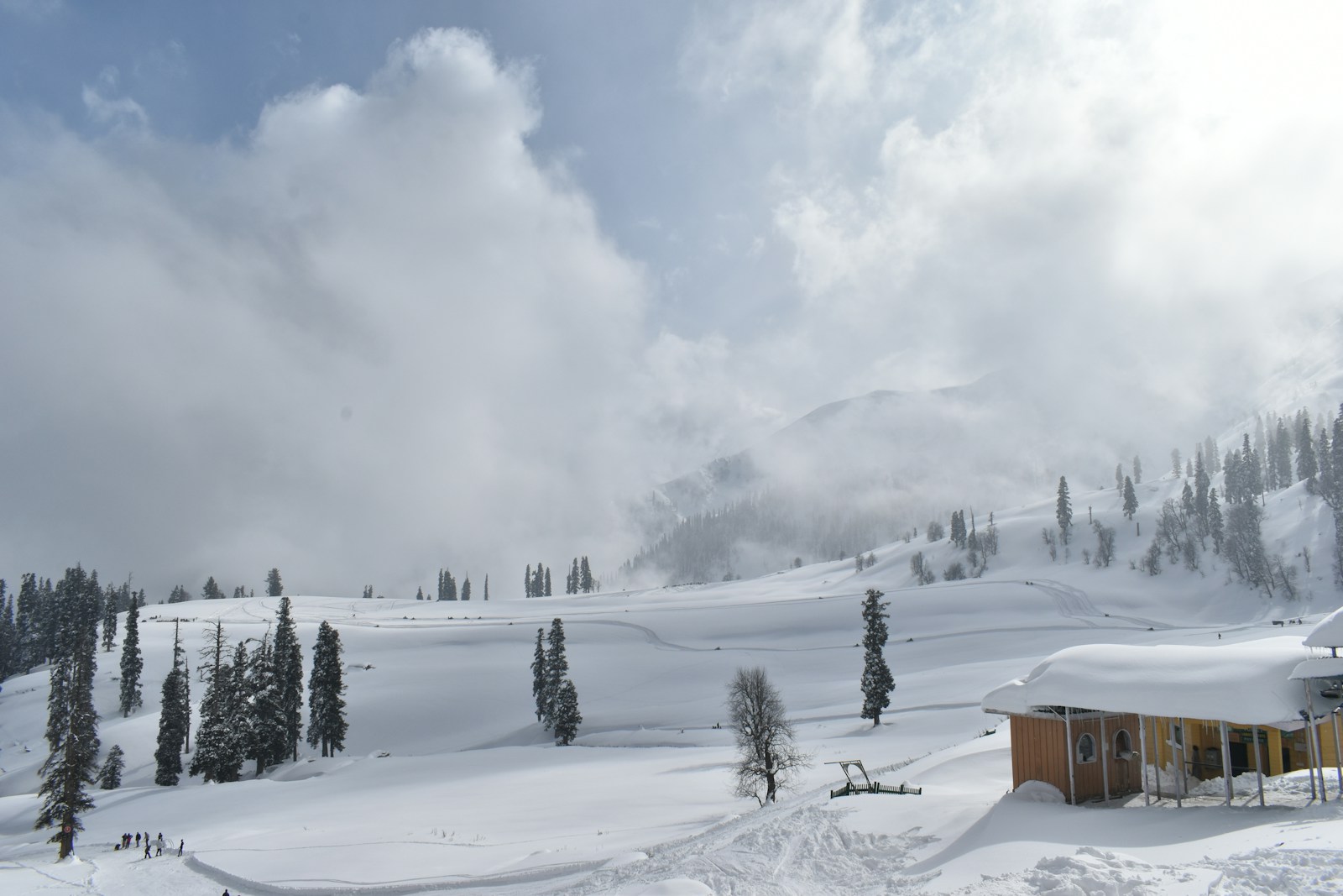 a snow covered mountain with a small cabin in the foreground